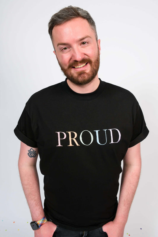 A beautiful black high quality oversized t-shirt with a pastel rainbow letters spelling out 'PROUD.'
