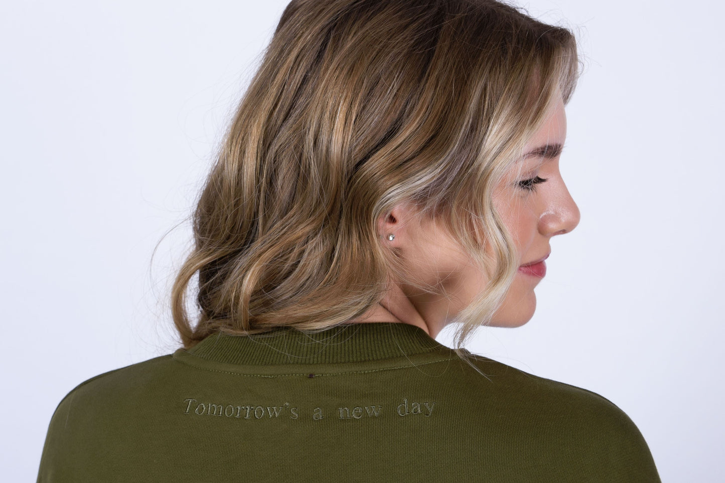 Our Surviving khaki green embroidered jumper from our mental health clothing collection, featuring the uplifting message "Tomorrow's a new day" elegantly stitched on the back to inspire resilience.