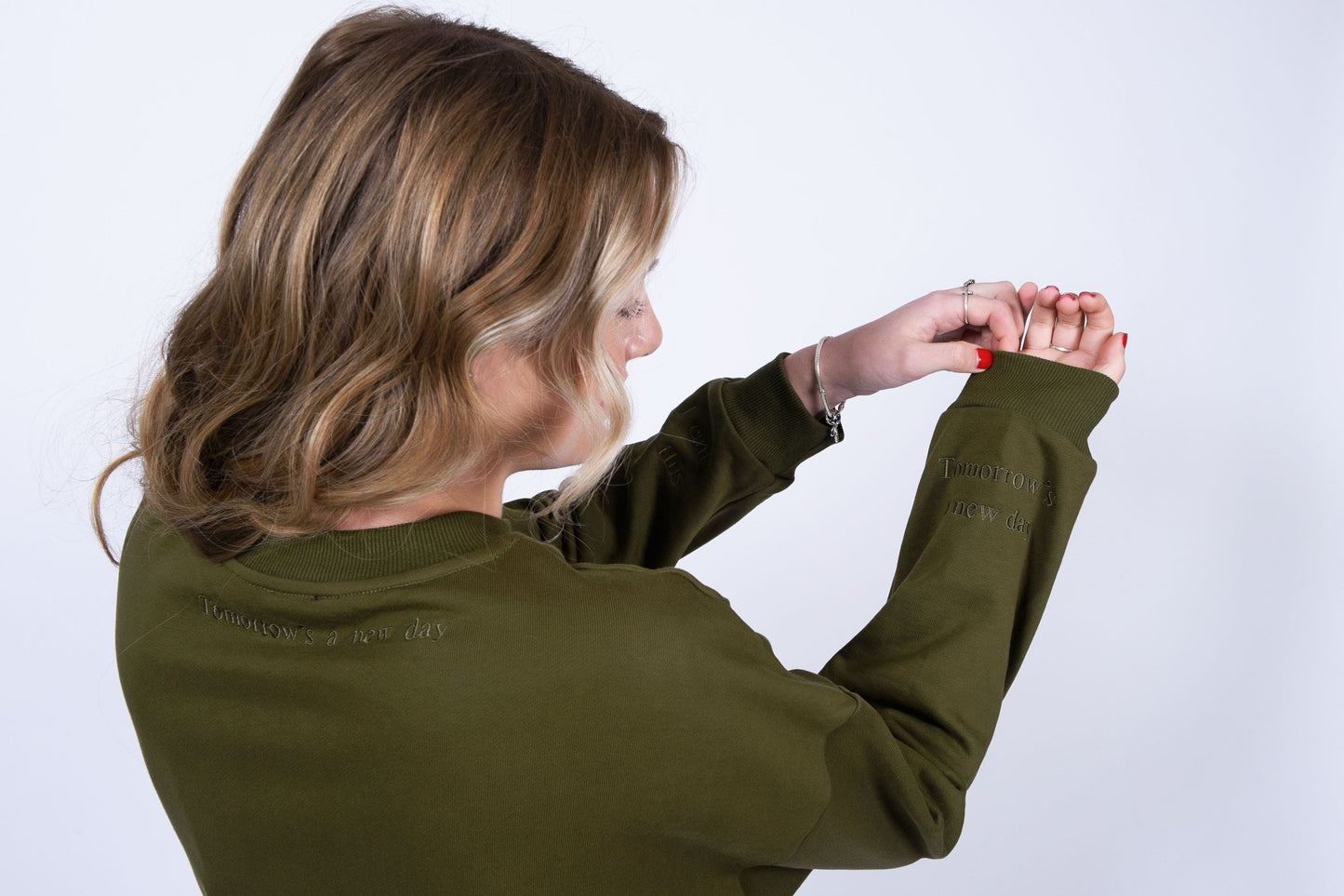 Our Surviving khaki green embroidered jumper from our mental health clothing collection, featuring the uplifting message "Surviving" across the chest. Additional encouraging phrases include "Tomorrow's a new day" elegantly stitched to inspire resilience.