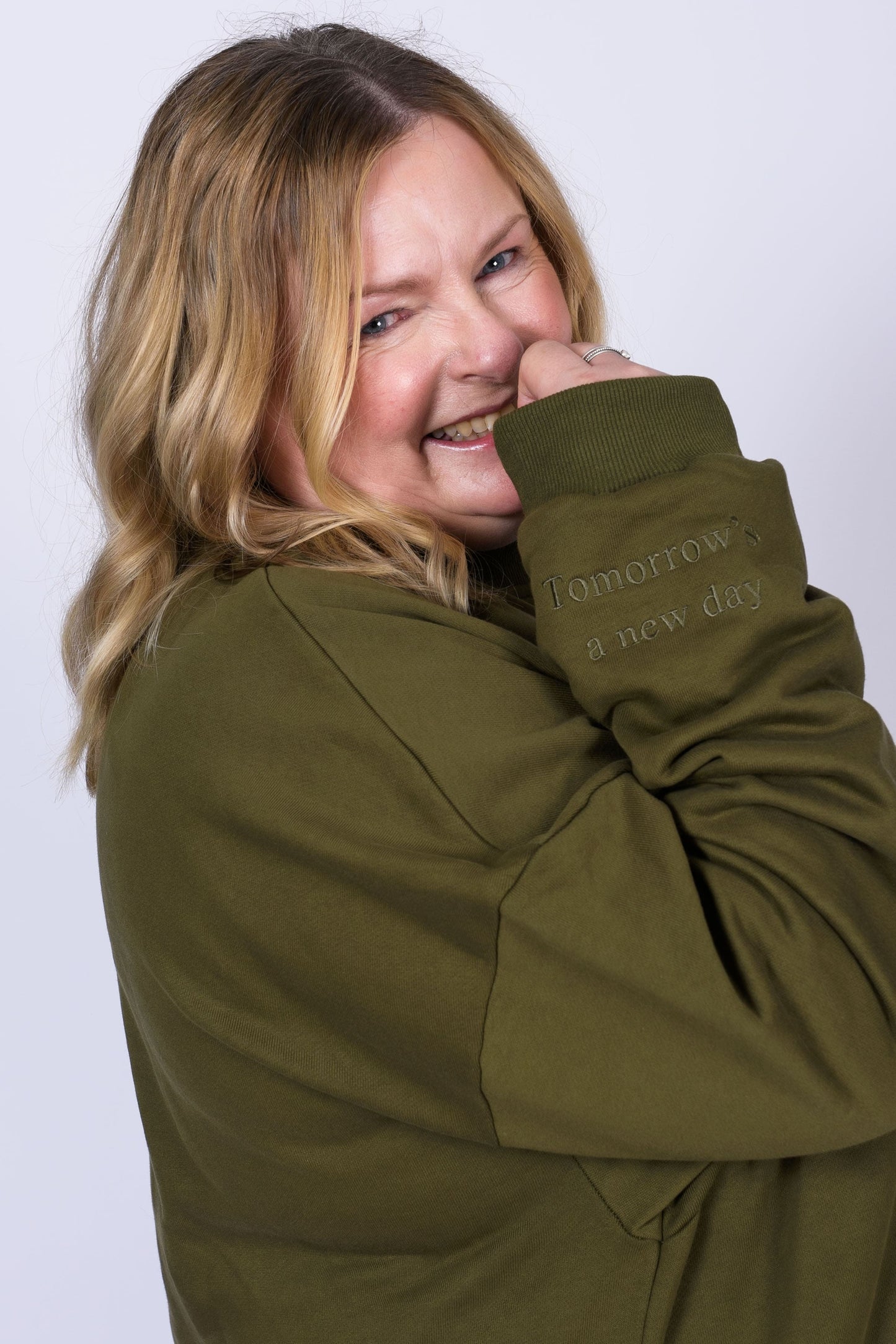 Our Surviving khaki green embroidered jumper from our mental health clothing collection, featuring the uplifting message "Surviving" across the chest. Additional encouraging phrases include "Tomorrow's a new day" elegantly stitched to inspire resilience.