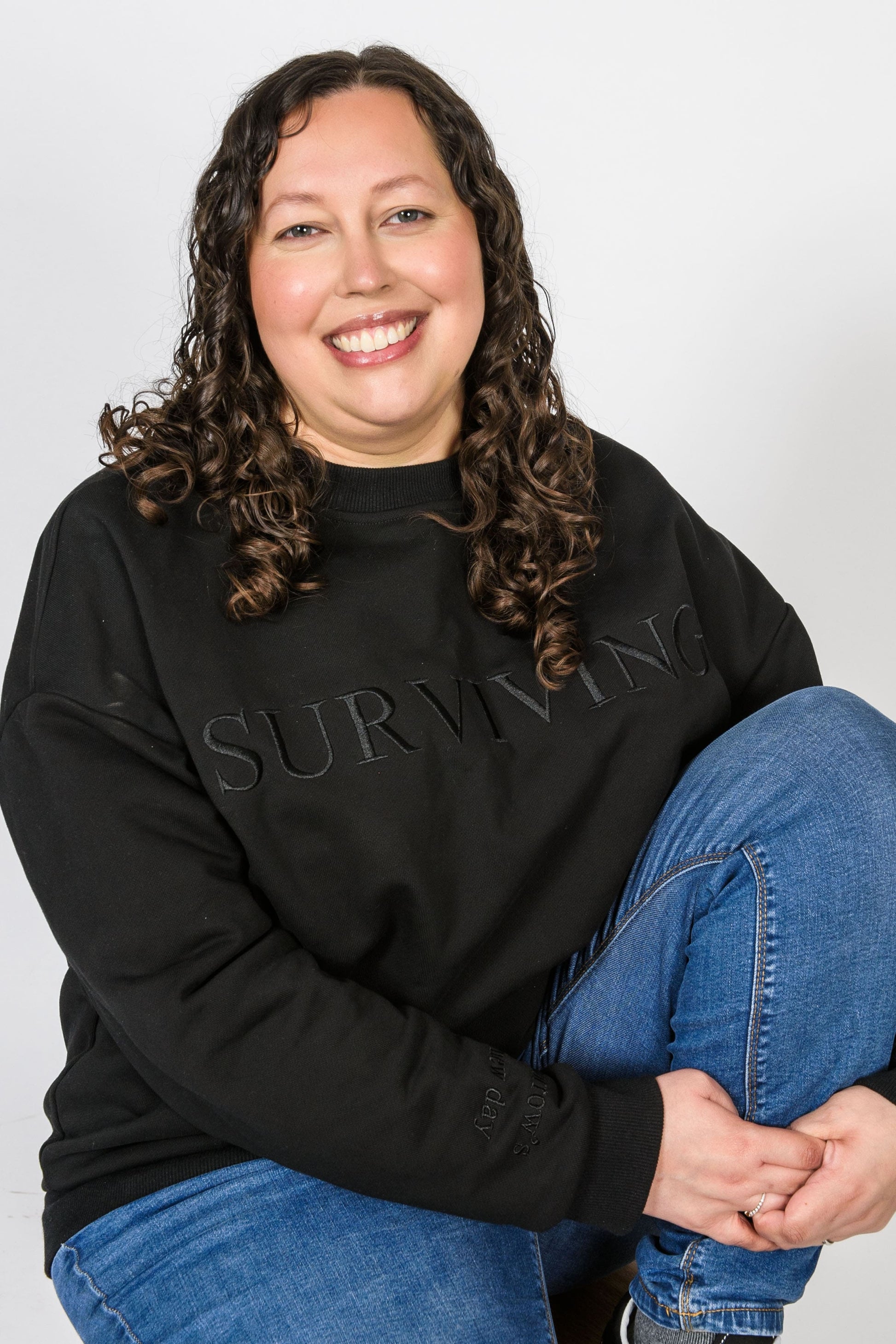 Our Surviving black embroidered jumper from our mental health clothing collection, featuring the uplifting message "Surviving" across the chest. Additional encouraging phrases include "Tomorrow's a new day" and "I can do this," elegantly stitched to inspire resilience.