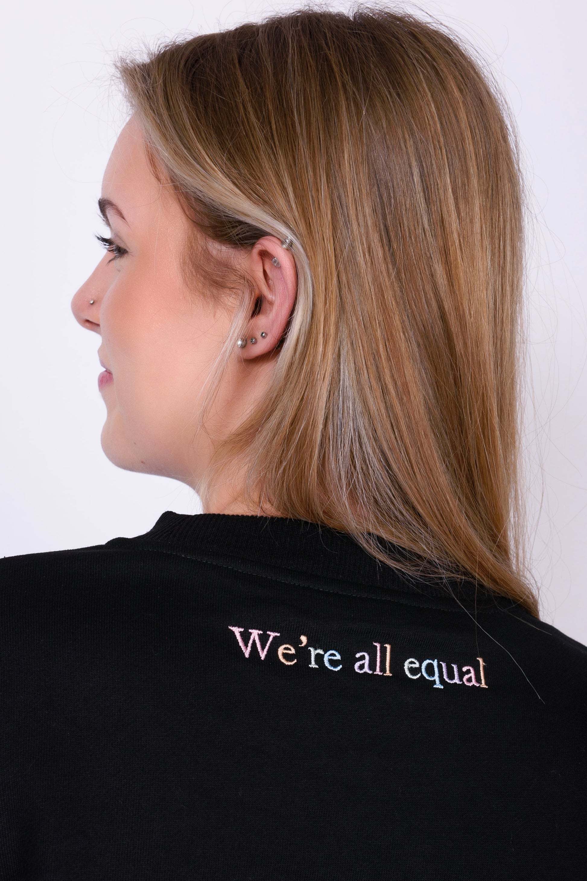 A beautiful black high quality oversized jumper with a Pastel rainbow letters spelling out 'PROUD.' The photo shows the back of the t-shirt which reads in Pastel rainbow colours 'We're all equal'