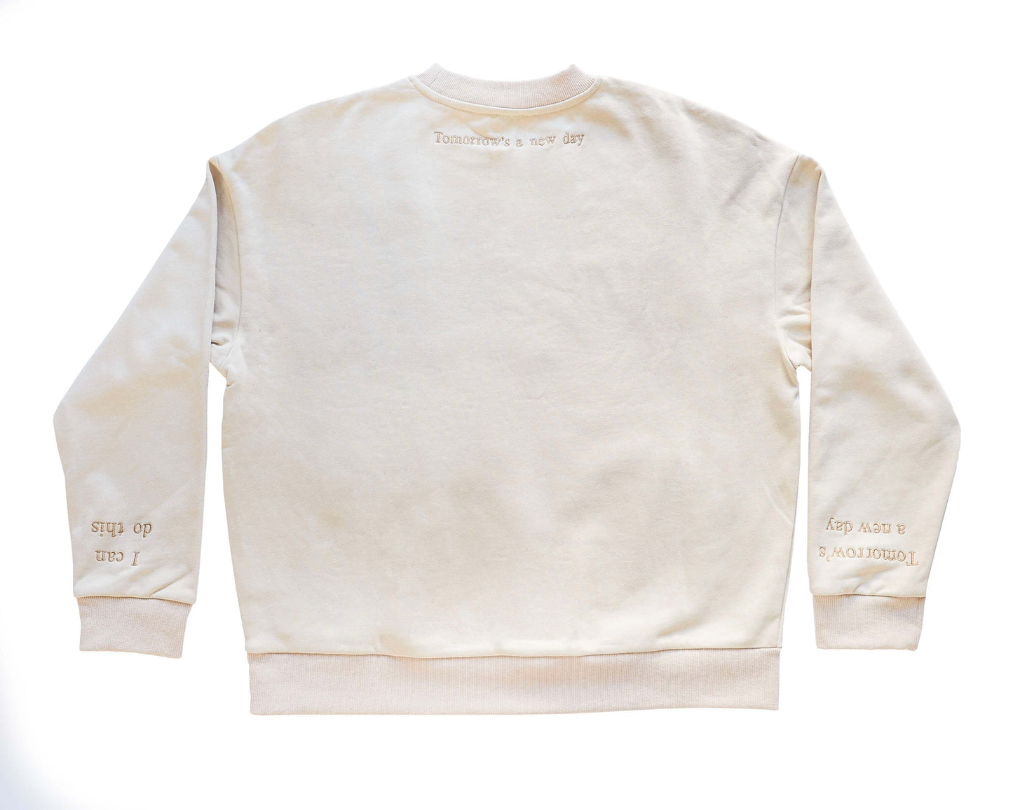 A beige, cotton oversized jumper with beautiful champaign embroidery it reads 'Surviving' in large capital letters across the chest and has reassuring messages on the cuffs that read 'I can do this' and 'Tomorrow's a new day '