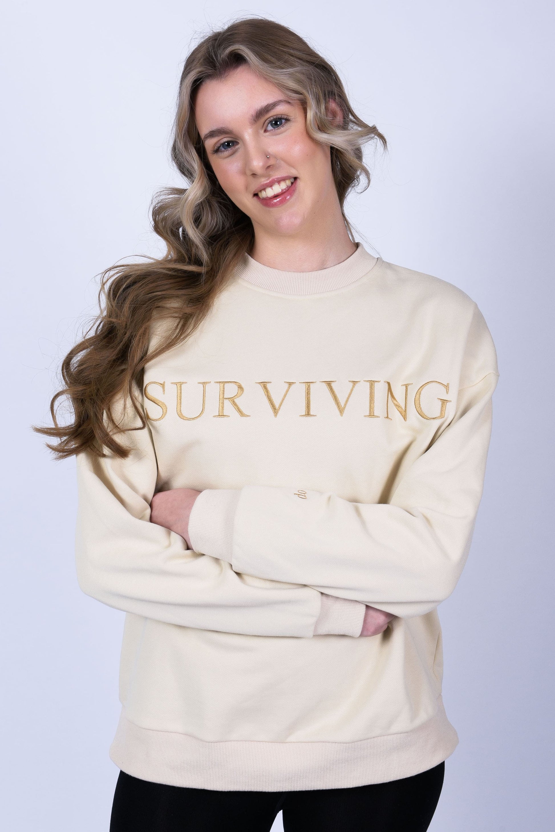 Our Surviving beige embroidered jumper from our mental health clothing collection, featuring the uplifting message "Surviving" across the chest and phrases include "Tomorrow's a new day" and "I can do this" elegantly stitched to inspire resilience.