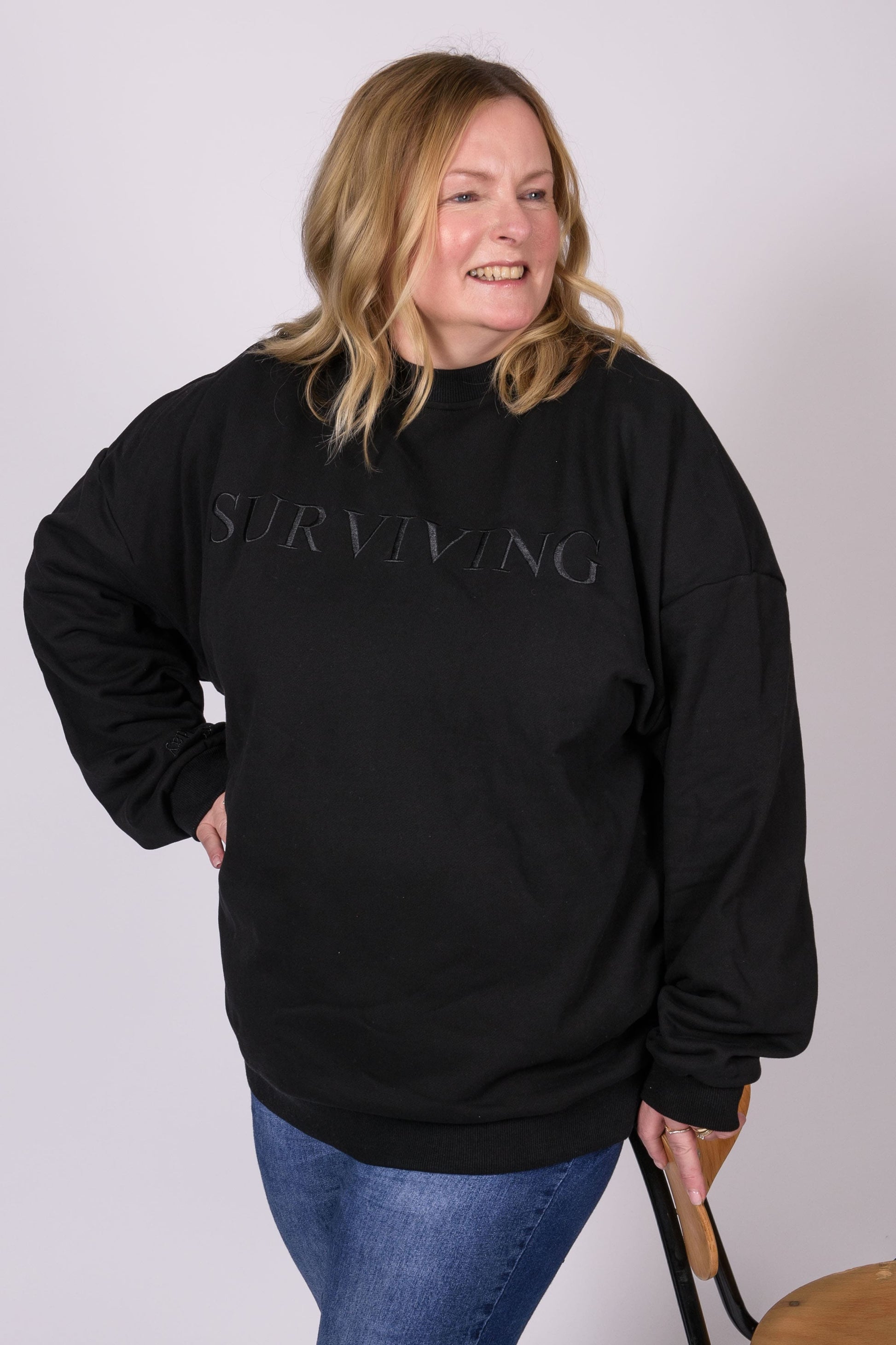 Our Surviving black embroidered jumper from our mental health clothing collection, featuring the uplifting message "Surviving" across the chest. Additional encouraging phrases include "Tomorrow's a new day" and "I can do this," elegantly stitched to inspire resilience.