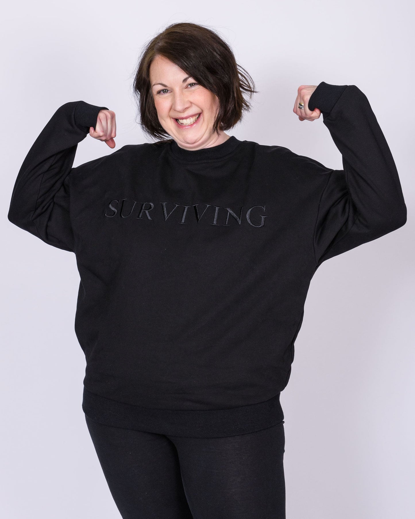 Our Surviving black embroidered jumper from our mental health clothing collection, featuring the uplifting message "Surviving" across the chest. Additional encouraging phrases include "Tomorrow's a new day" and "I can do this," elegantly stitched to inspire resilience.